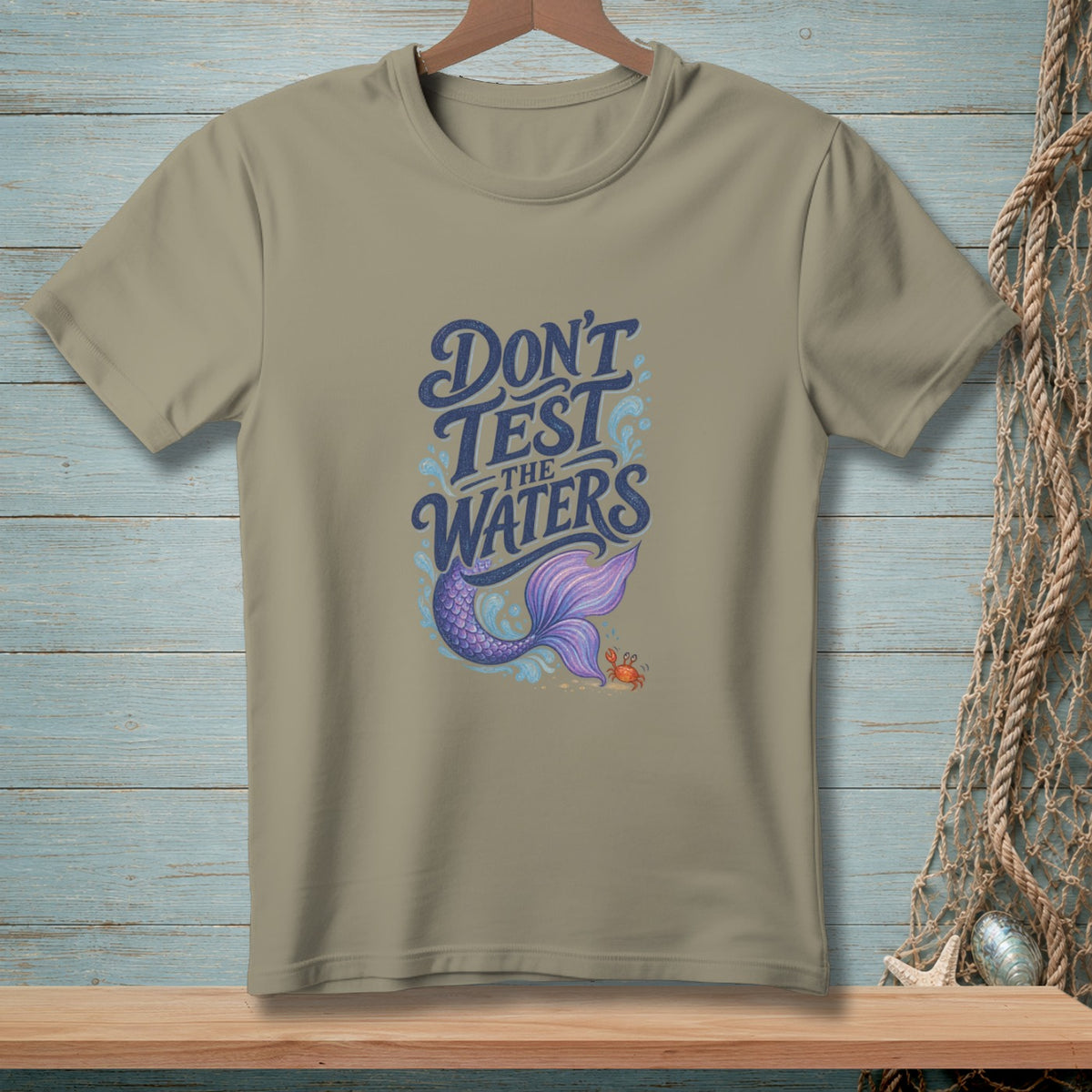 Tan t-shirt with "Don't Test The Waters" text, mermaid tail, and crab graphic.