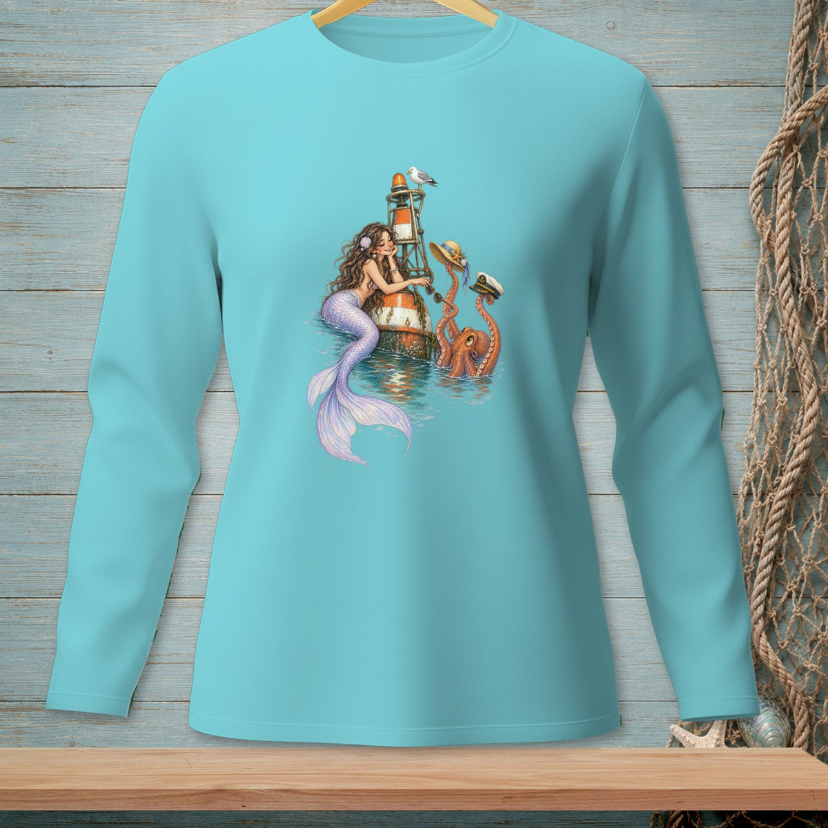 Mermaid with octopus by a lighthouse, wearing hats, on teal long-sleeve shirt.