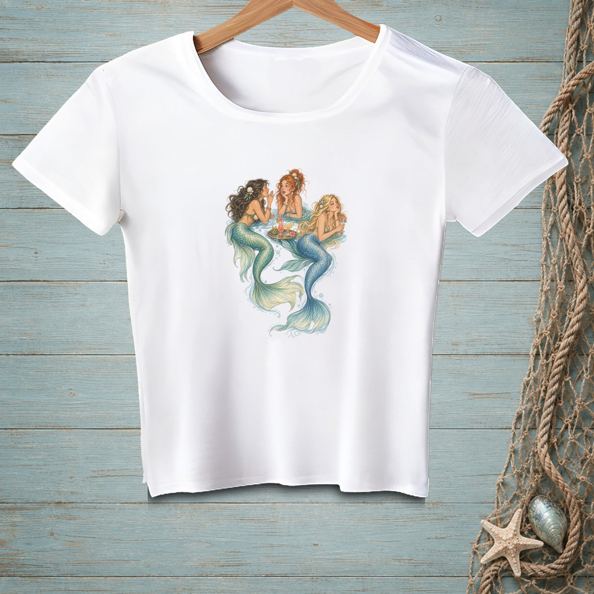 White t-shirt with illustration of three mermaids drinking at a circular table.