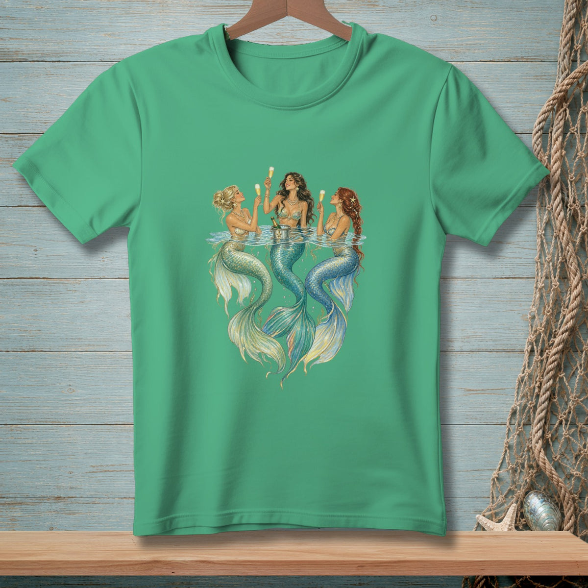 Three mermaids with champagne toasting on a teal t-shirt.
