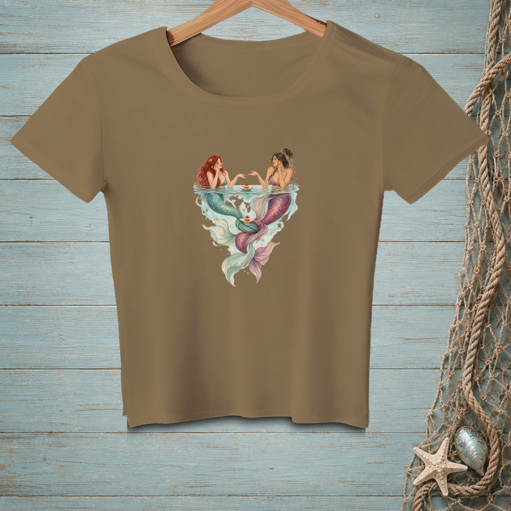 Two mermaids sit in water with cakes, their tails fanning out below.