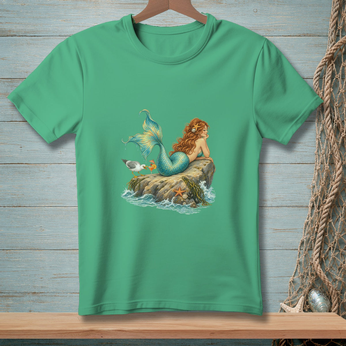 Green t-shirt with a mermaid lounging on a rock with a seagull.