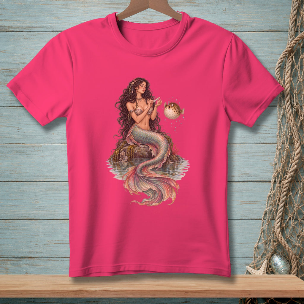 Pink t-shirt with a mermaid filing a pufferfish's nails.