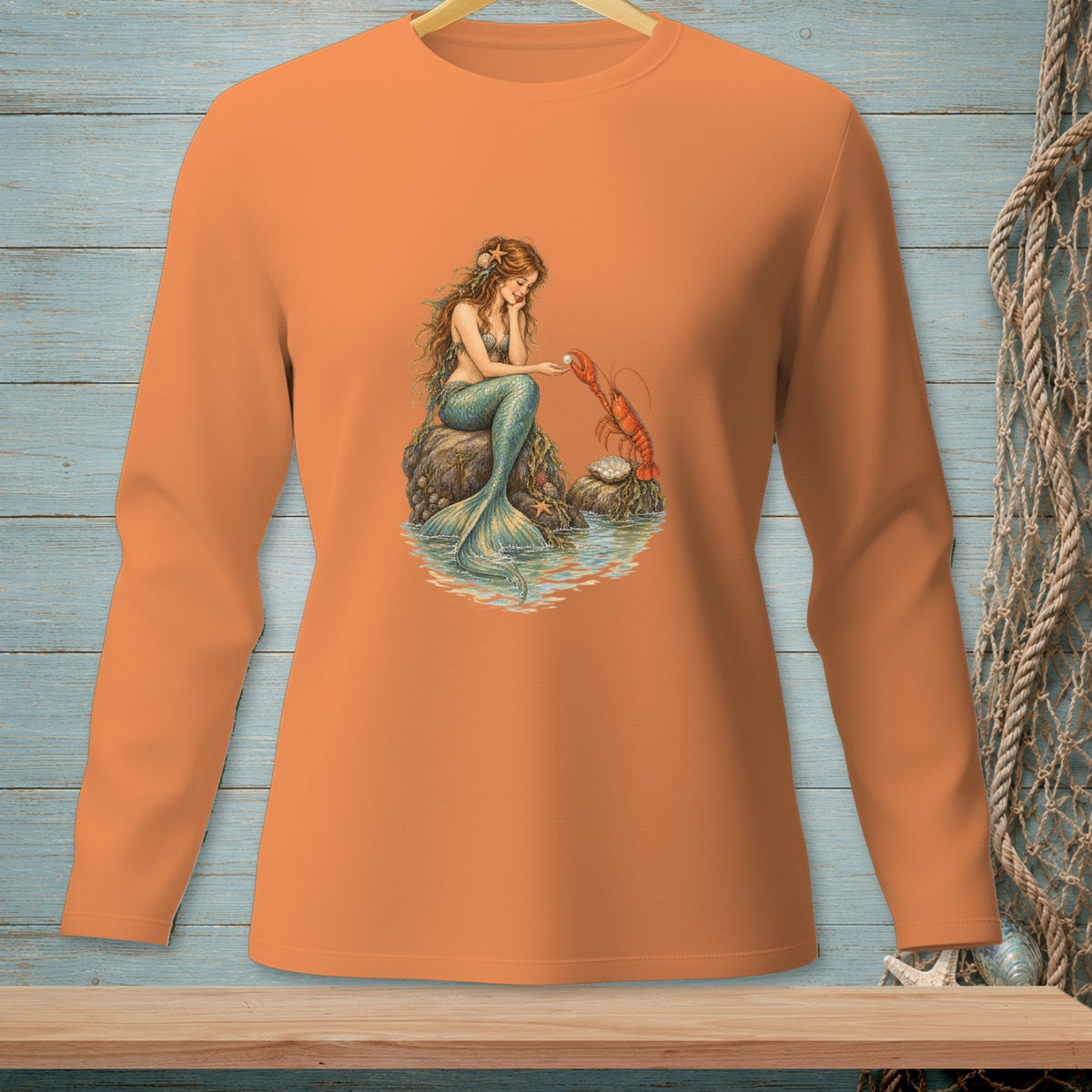 Long sleeve orange shirt with a mermaid holding a pearl next to a lobster.