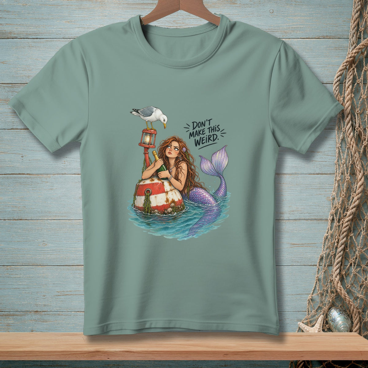 T-shirt graphic of mermaid on buoy with seagull and text "Don't make this weird."