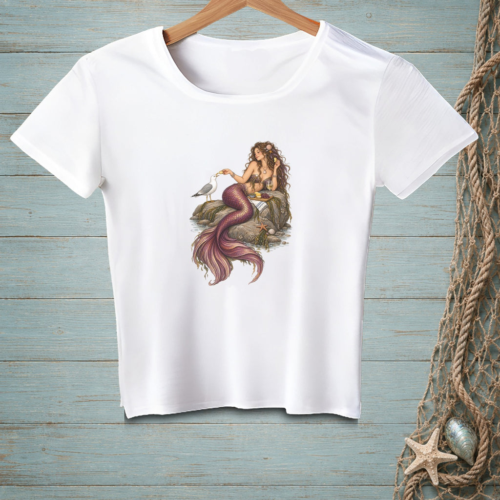White t-shirt with a detailed illustration of a mermaid sitting on rocks with a seagull.