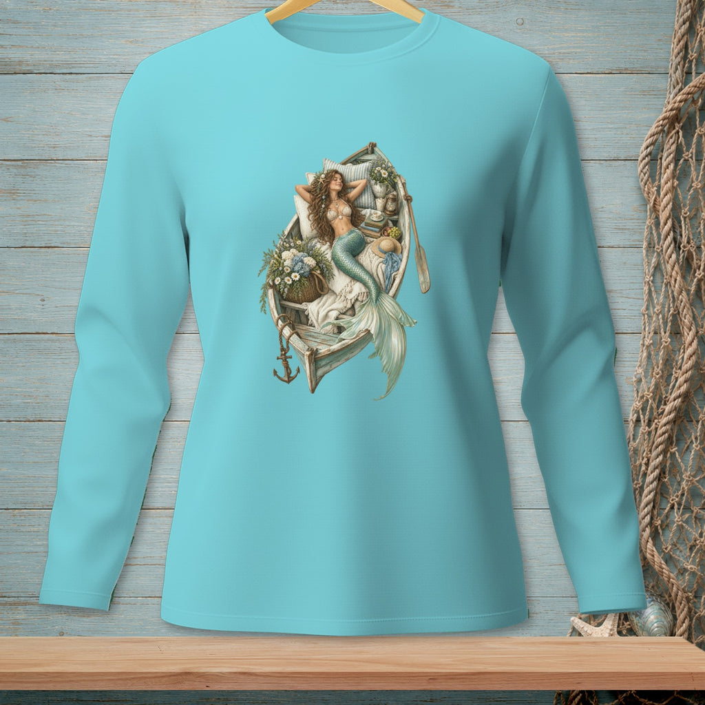 Mermaid lounging in a boat with flowers, oars, and anchor graphic on a light blue long-sleeve shirt.