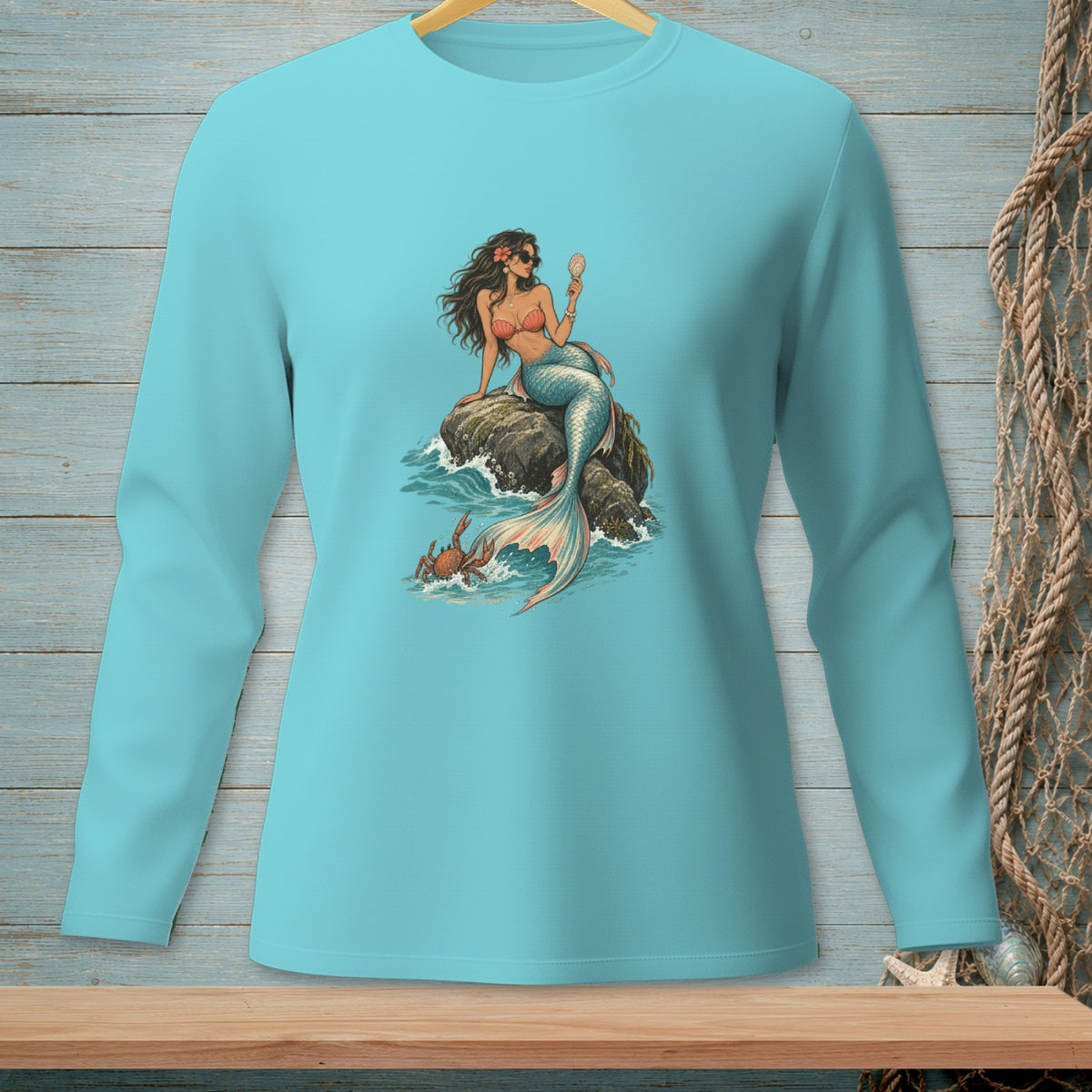 Teal long-sleeve shirt featuring a mermaid and crab graphic with a seashell.
