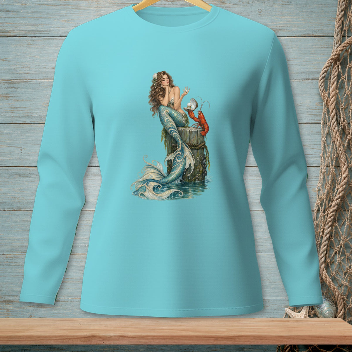 Mermaid with lobster and pearl on a wooden post, printed on a teal long-sleeve shirt.