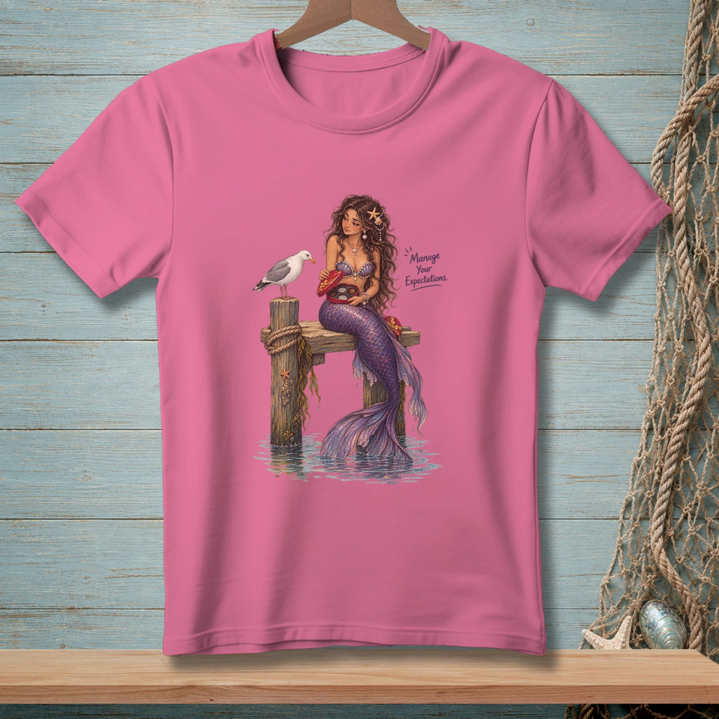 Pink t-shirt featuring a mermaid sitting on a dock with a seagull and text.