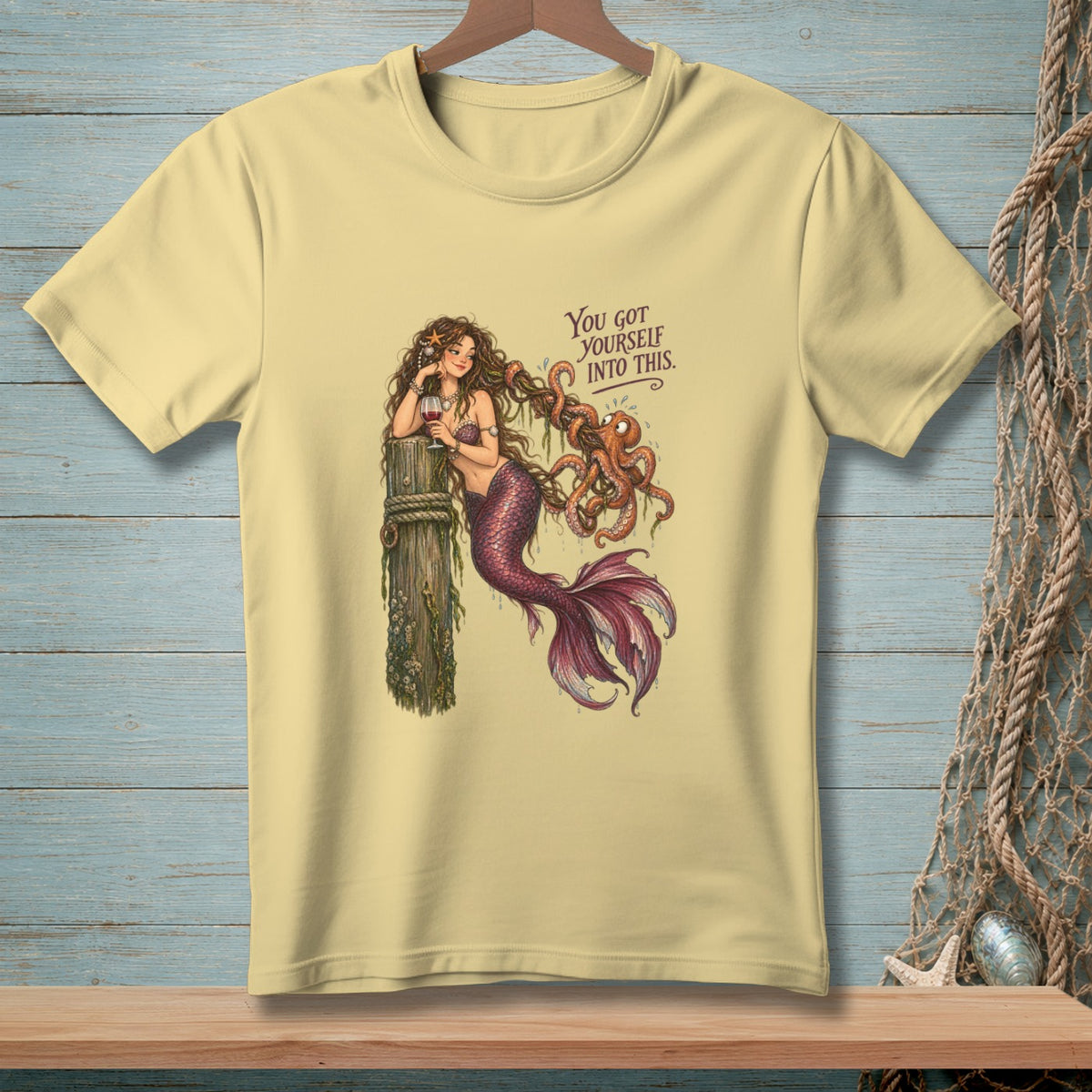 Light yellow t-shirt with a mermaid and octopus graphic and the text "You got yourself into this."