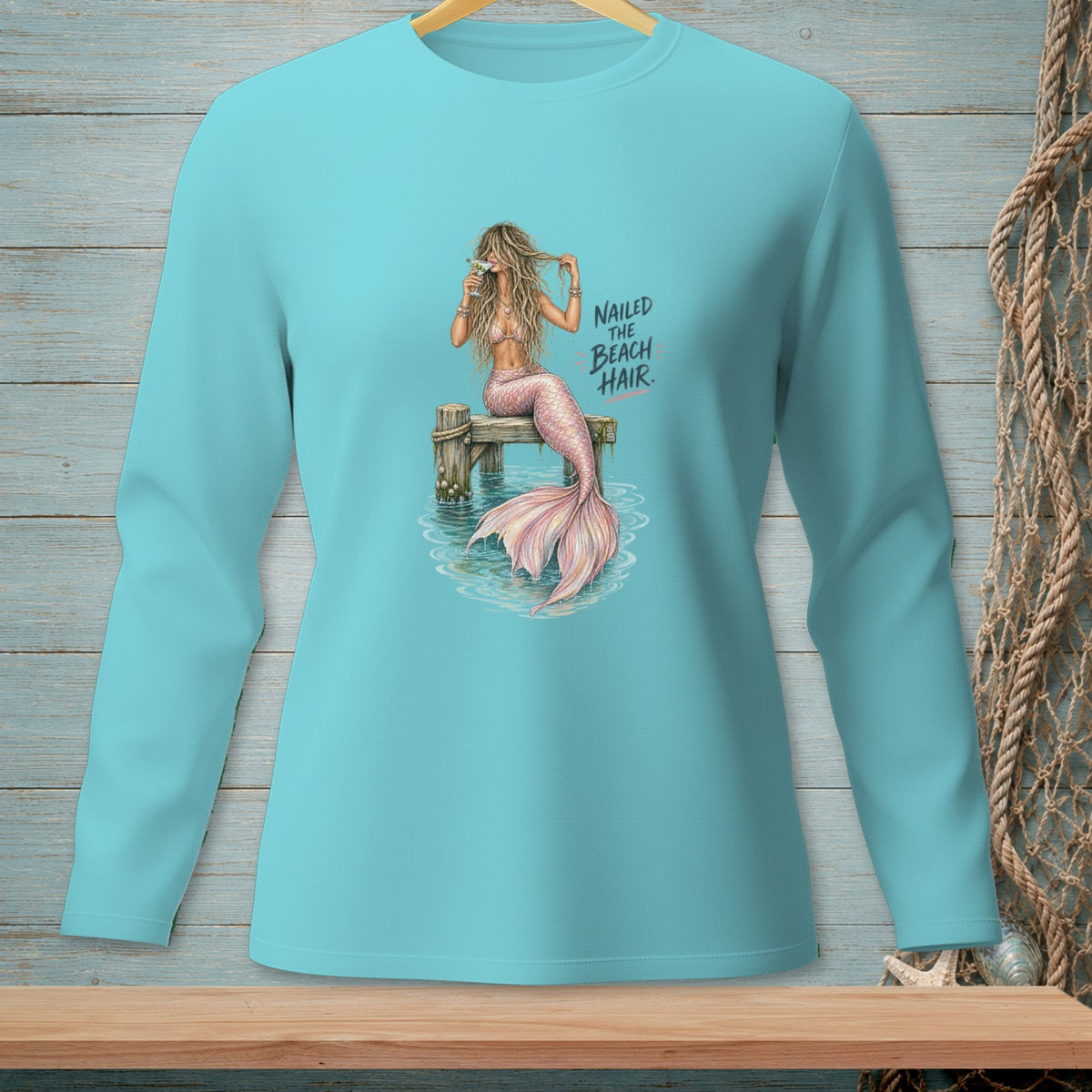 Mermaid on pier with drink and text "NAILED THE BEACH HAIR."