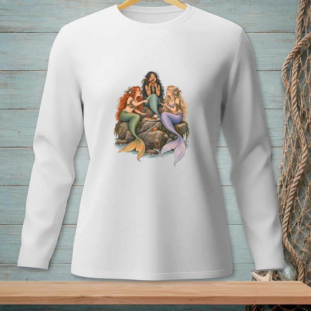Three mermaids sit on rocks sharing a cake.
