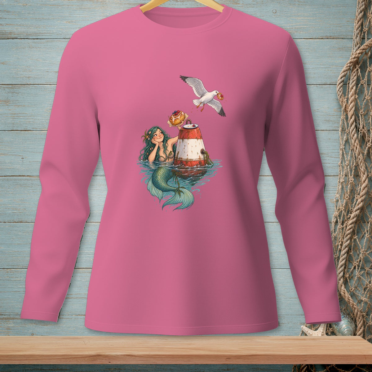 Pink long-sleeve shirt featuring a mermaid with a seagull stealing a donut from a buoy.