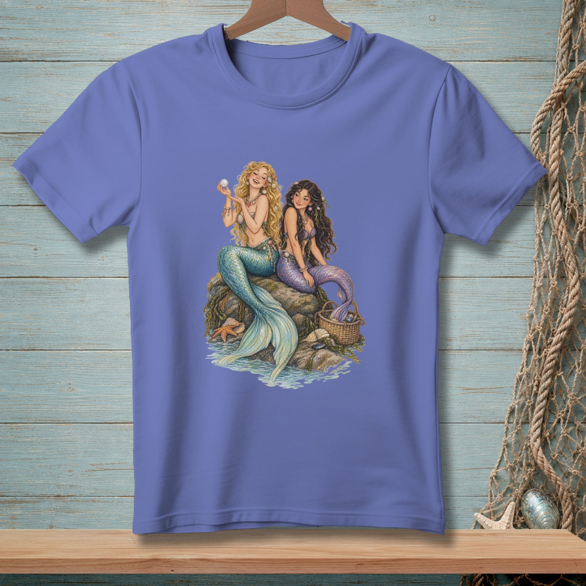 Two mermaids with colorful tails sit on rocks near the water, one holding a pearl.