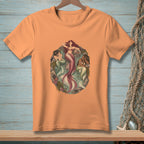 Orange t-shirt featuring three artistic mermaids with pink and green tails.