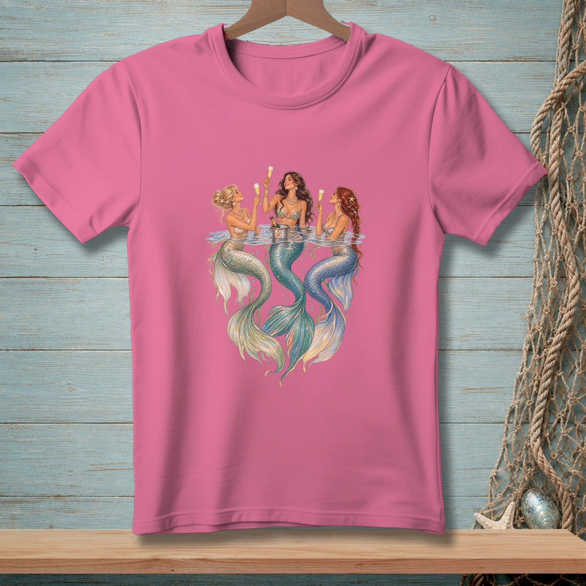 Three mermaids with champagne glasses enjoy a drink in the water.