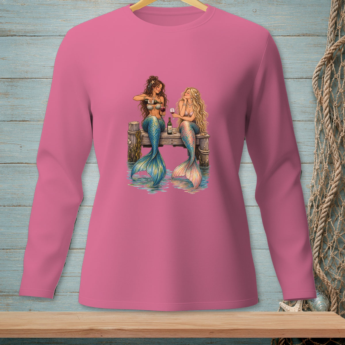 Two mermaids sitting on a dock, one pouring wine, with ocean background.