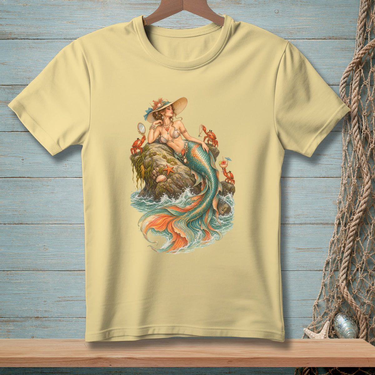 Yellow t-shirt with a vintage mermaid illustration on a rock surrounded by crabs and ocean waves.