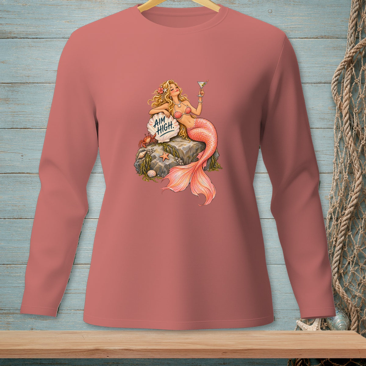 Pink long-sleeve shirt with a graphic of a mermaid holding a drink and a sign saying "AIM HIGH."