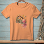 Peach t-shirt with a detailed illustration of a sleeping mermaid surrounded by coral and fish.