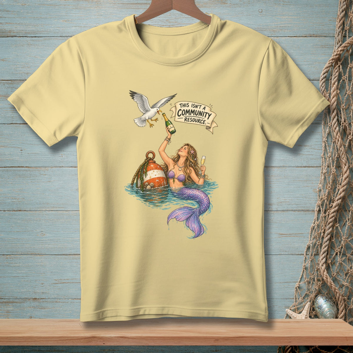T-shirt graphic of mermaid with champagne and a seagull, with text "This Isn't a Community Resource".