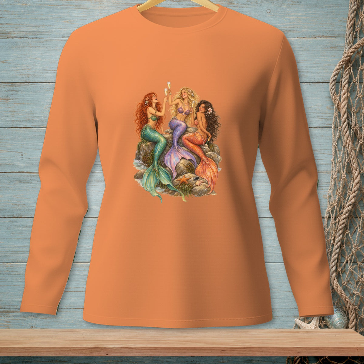 Orange long-sleeve shirt with a graphic of three mermaids toasting with champagne.