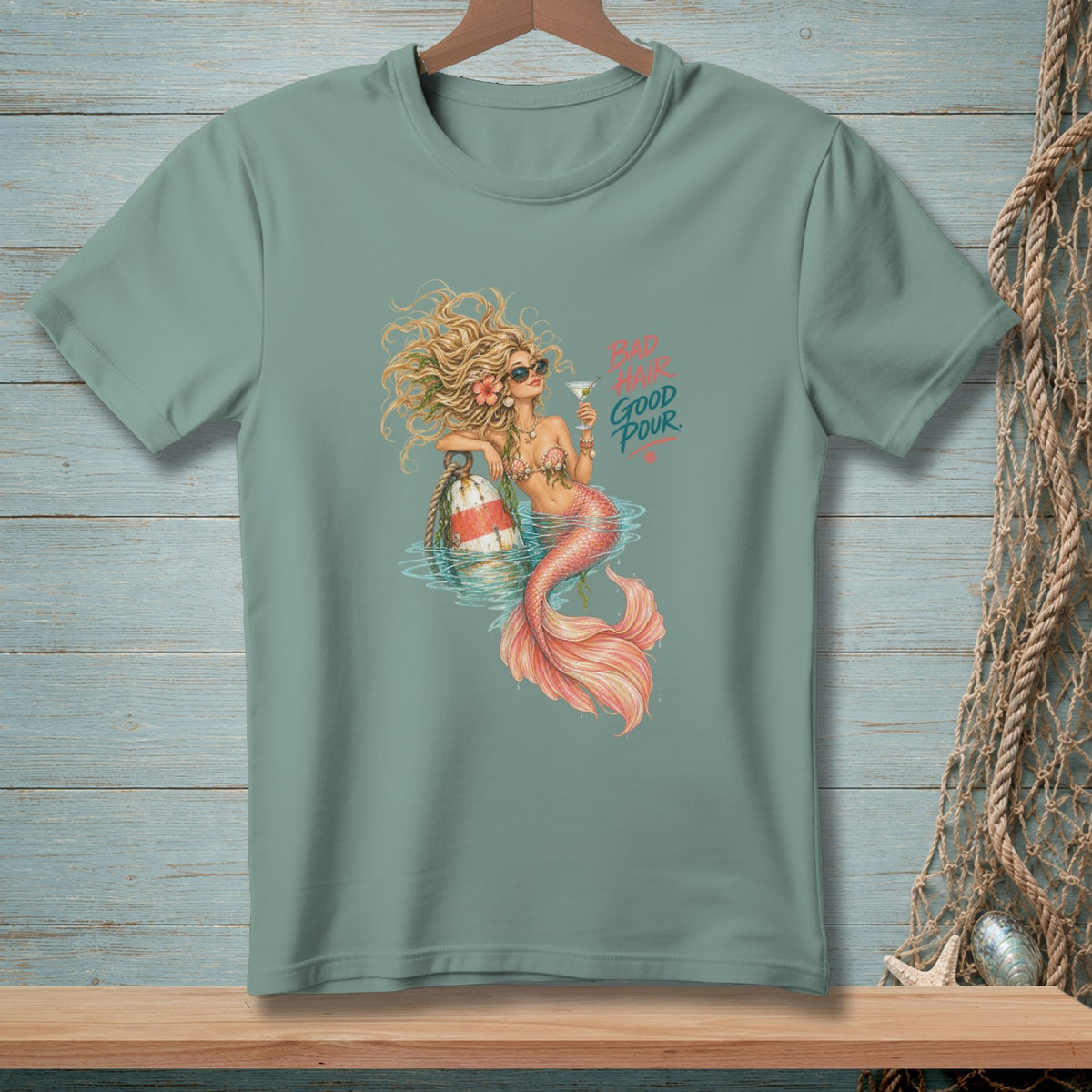 T-shirt graphic of a mermaid with sunglasses holding a martini, with text "BAD HAIR GOOD POUR."