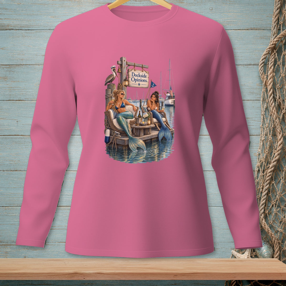 Two mermaids sit on a dock with a "Dockside Opinions" sign and sailboats in the background.
