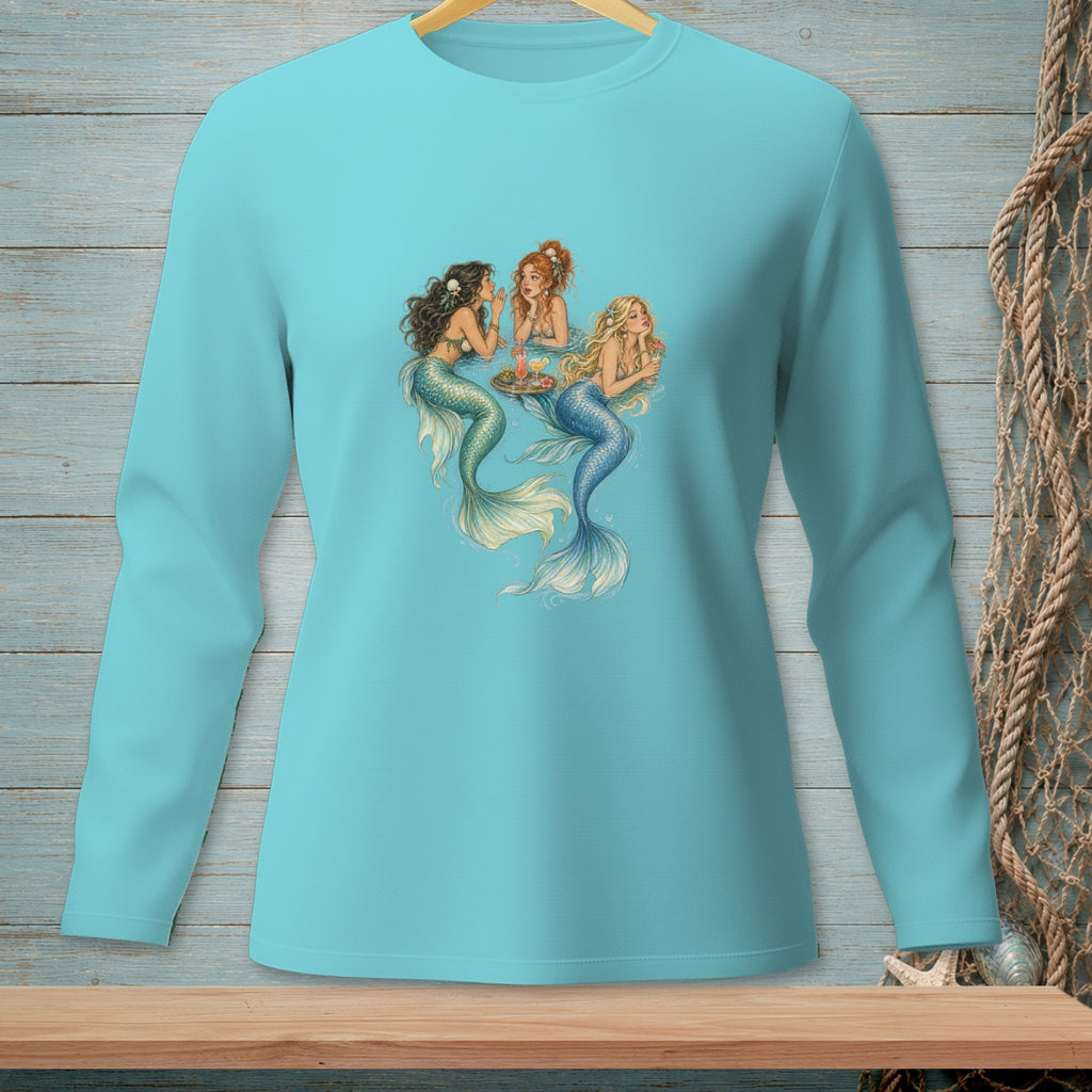 Three mermaids gather around a tray with drinks on a light blue long-sleeve shirt.