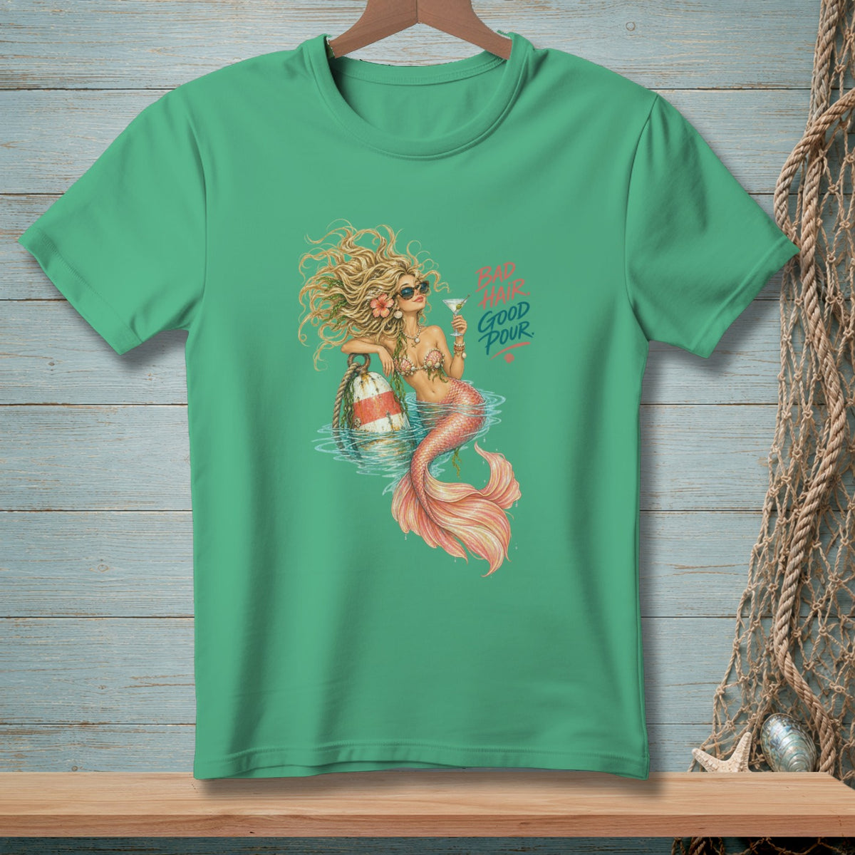 Green t-shirt featuring a mermaid with sunglasses holding a cocktail, text reads "BAD HAIR GOOD POUR".