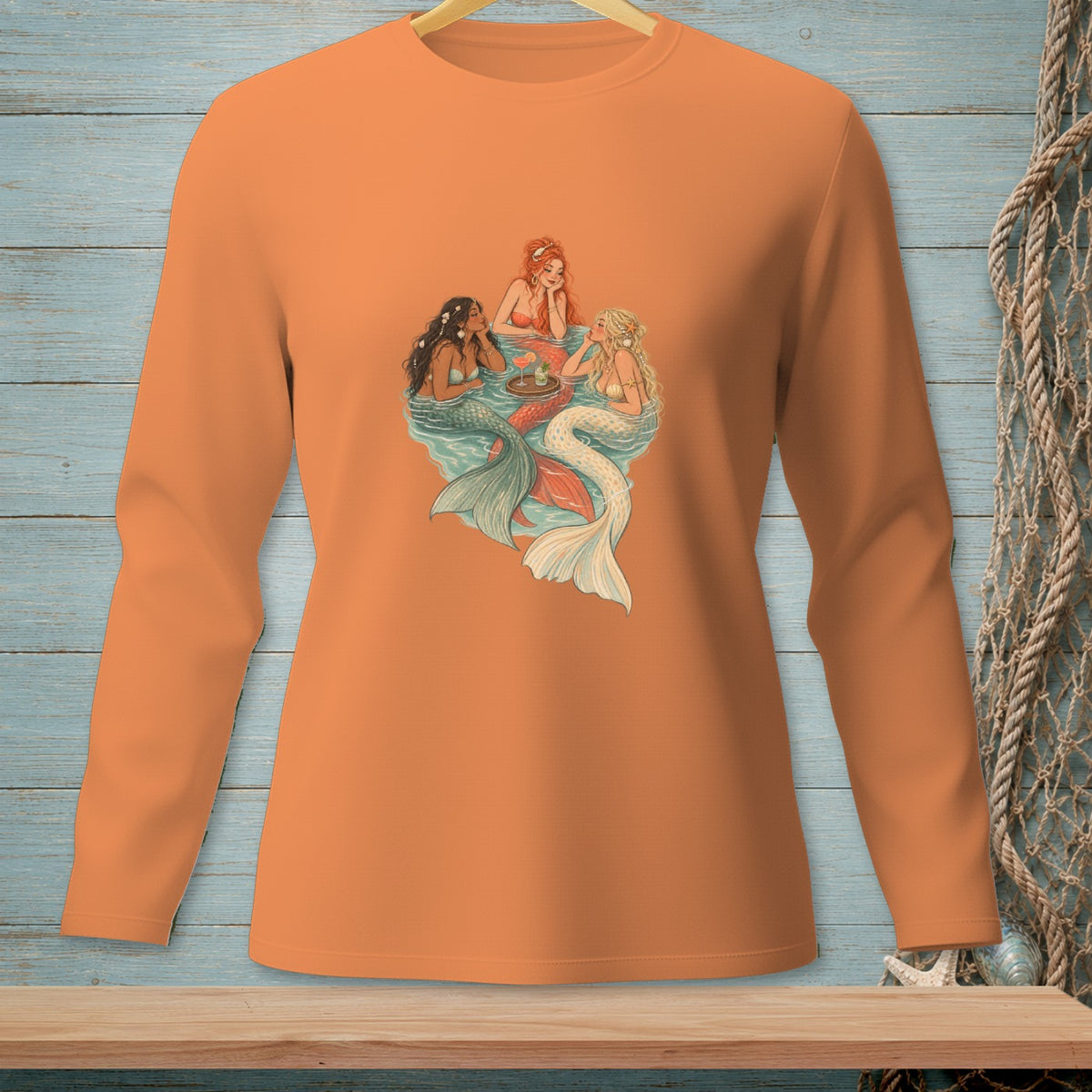 Orange long-sleeve shirt with three mermaids gathered around a tray of drinks.