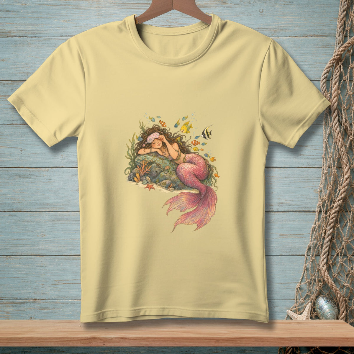 Yellow t-shirt with a sleeping mermaid design surrounded by fish and coral.