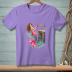 Purple t-shirt with a mermaid fishing from a wooden pier.