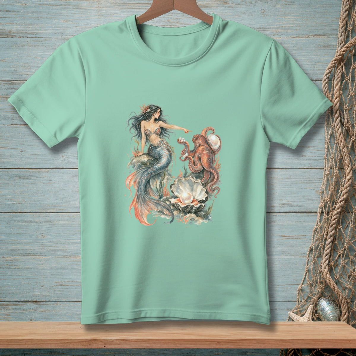 Mermaid pointing at an octopus near a pearl-filled seashell on a light teal shirt.