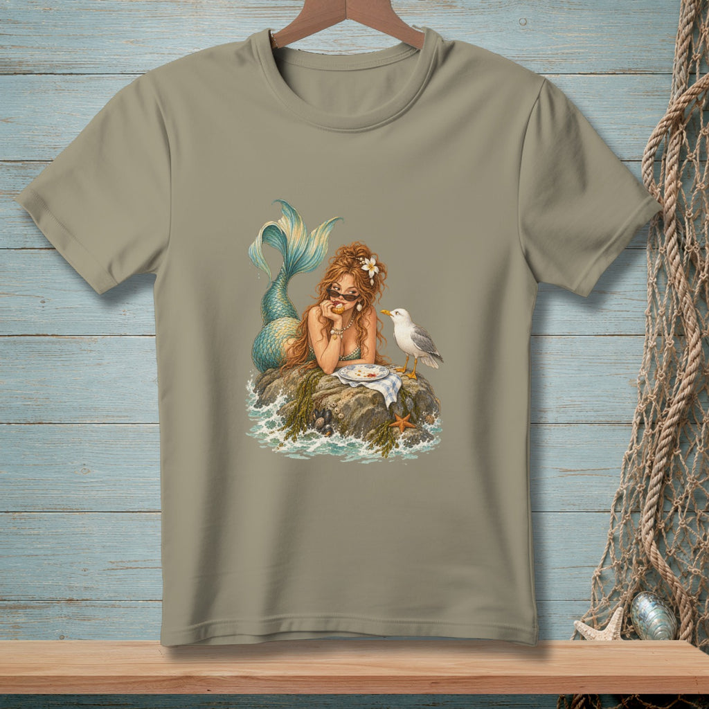 Mermaid with sunglasses sits on a rock with a plate of food and a seagull.