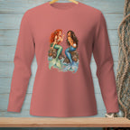 Two mermaids sit on rocks by the sea, one holding a pearl.