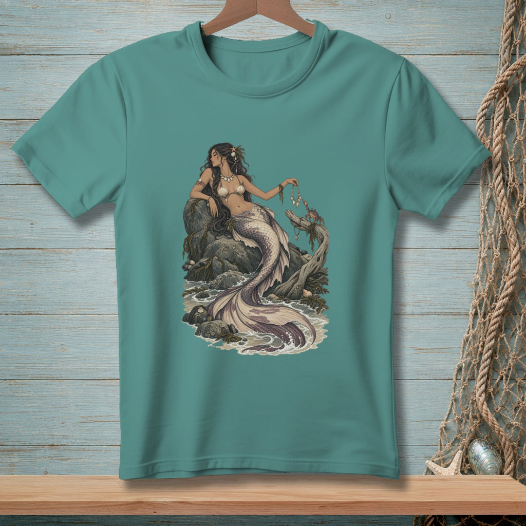 Teal t-shirt with a detailed illustration of a mermaid sitting on rocks by the sea.