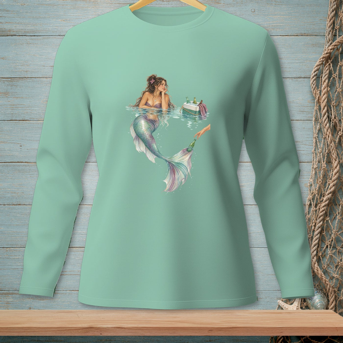 Mint long sleeve shirt with a graphic of a mermaid receiving a bottle from a hand.