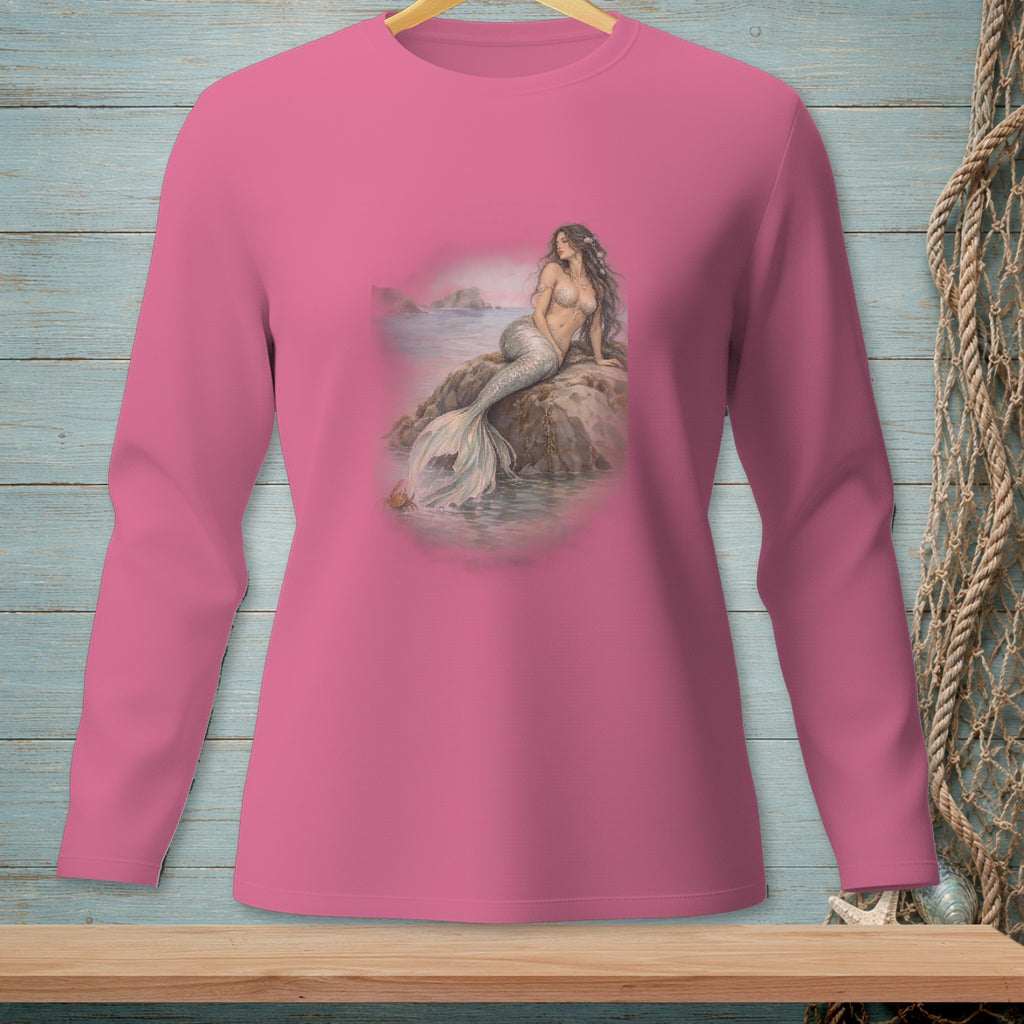 Pink long-sleeve shirt with a detailed mermaid sitting on rocks near the ocean.