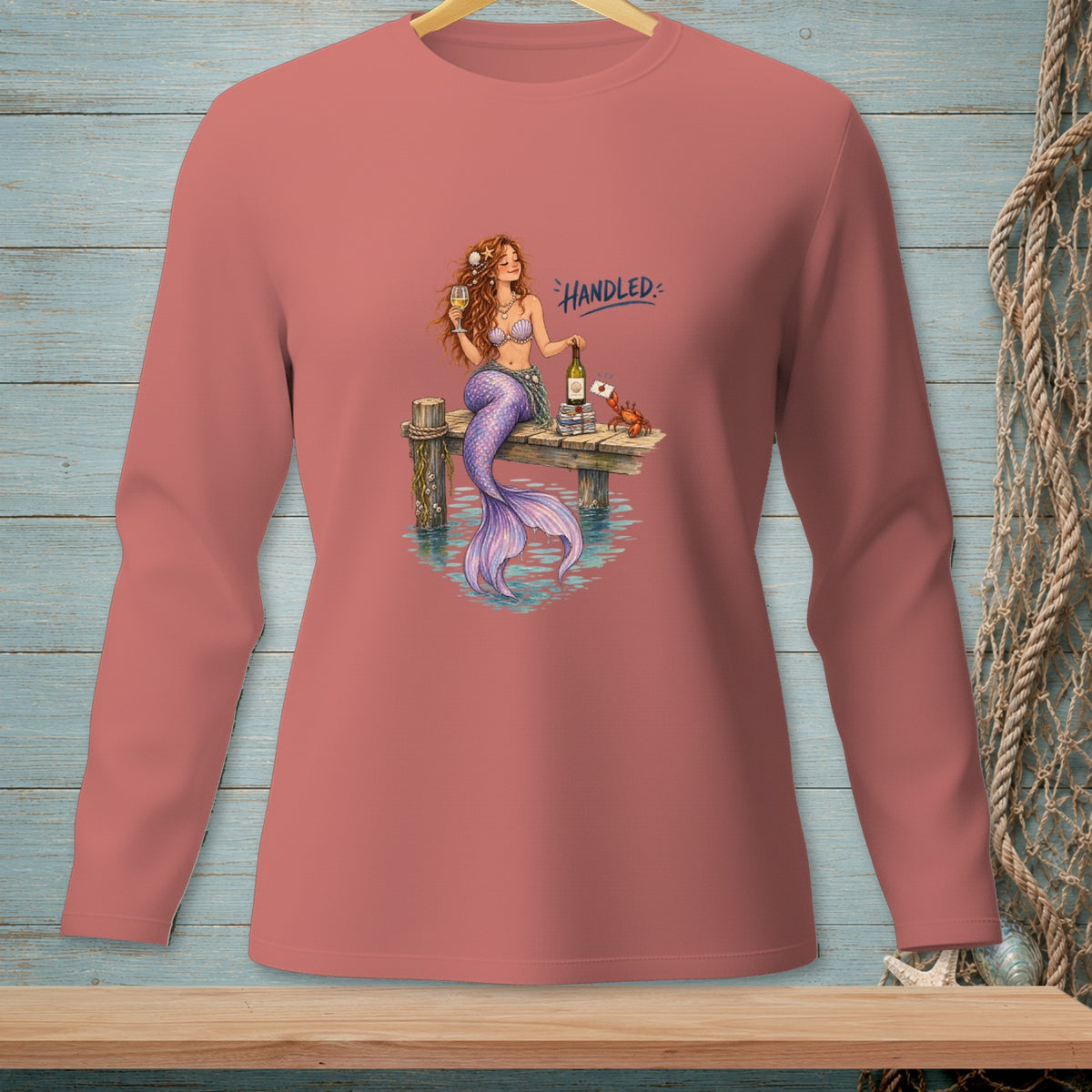 Mermaid on dock with wine, crab, and text "Handled".