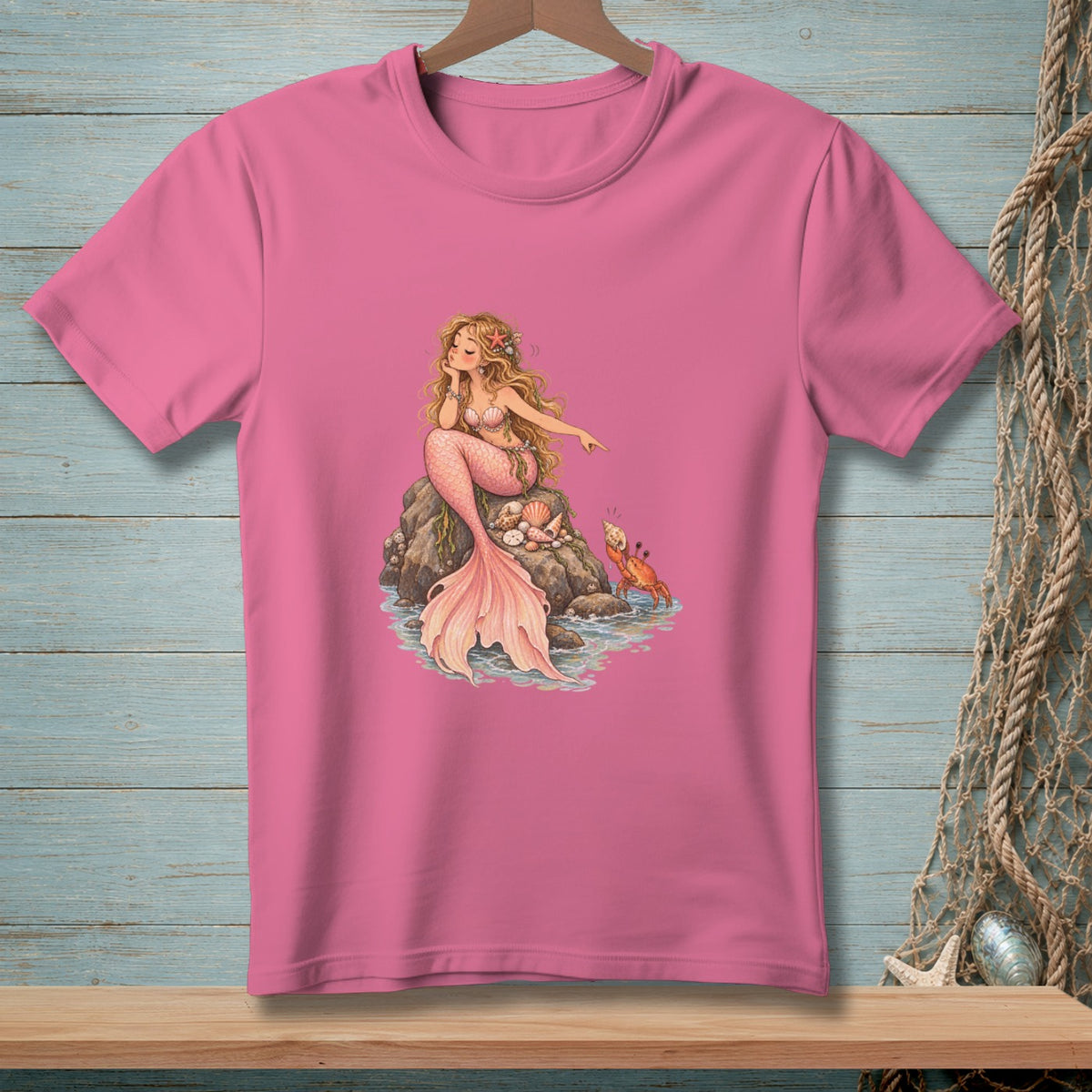 Pink t-shirt featuring a mermaid sitting on rocks with a crab nearby.