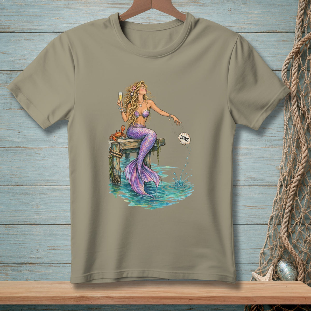 Mermaid with purple tail sits on dock, holding champagne, with a crab and a shell labeled "DONE".