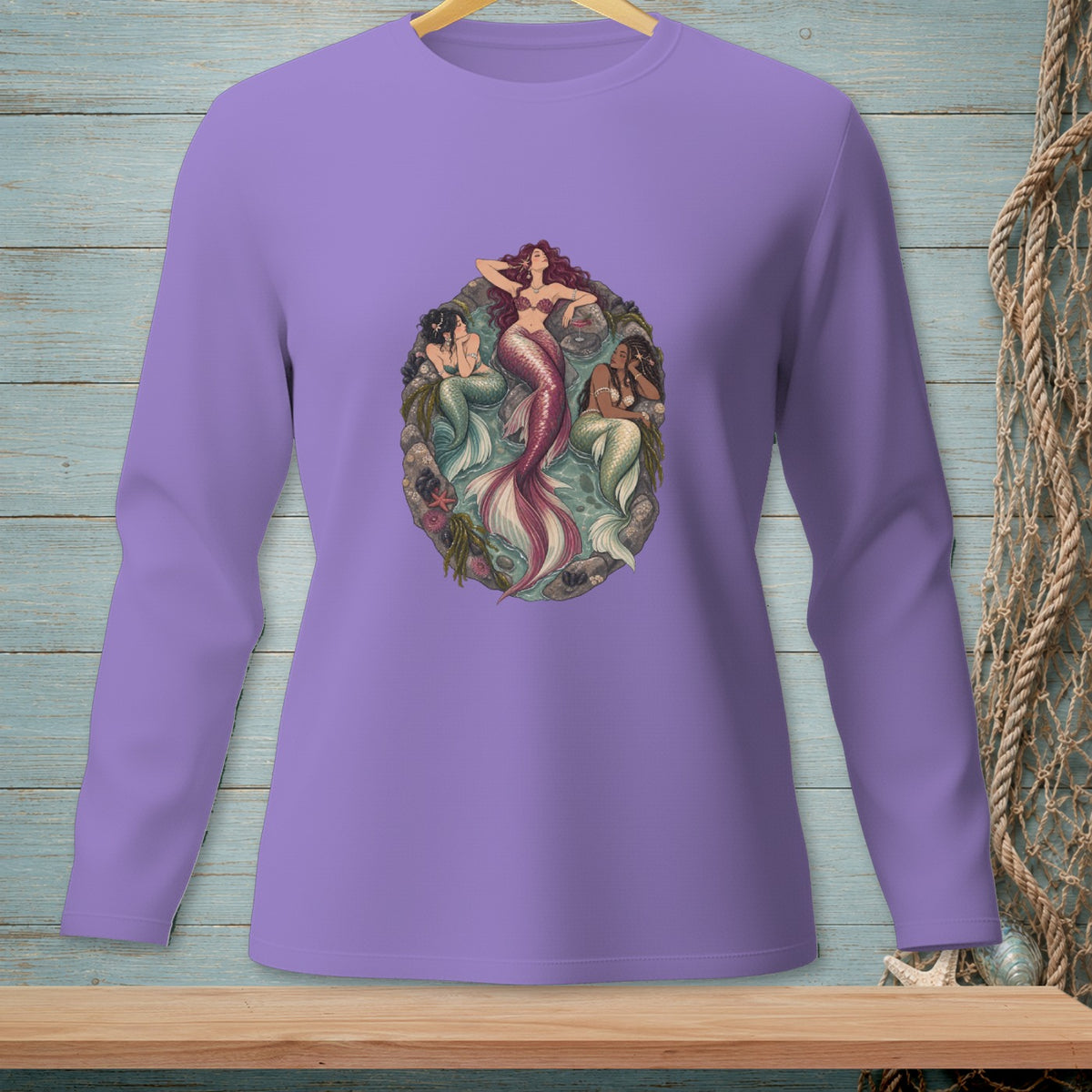 Lavender long-sleeve shirt with a circular graphic of three mermaids among rocks and seaweed.