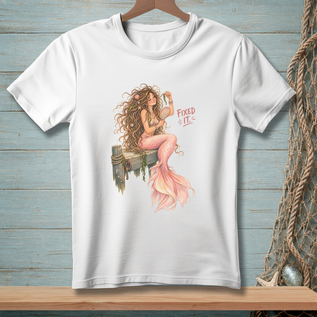 White t-shirt with a watercolor mermaid illustration and text "FIXED IT."