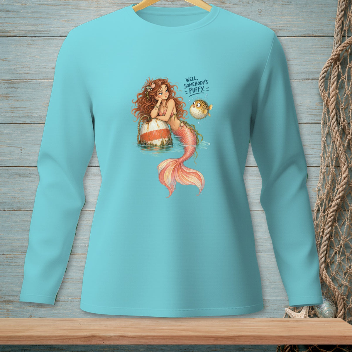 Mermaid with pufferfish and text "WELL, SOMEBODY'S PUFFY" on a teal long-sleeve shirt.