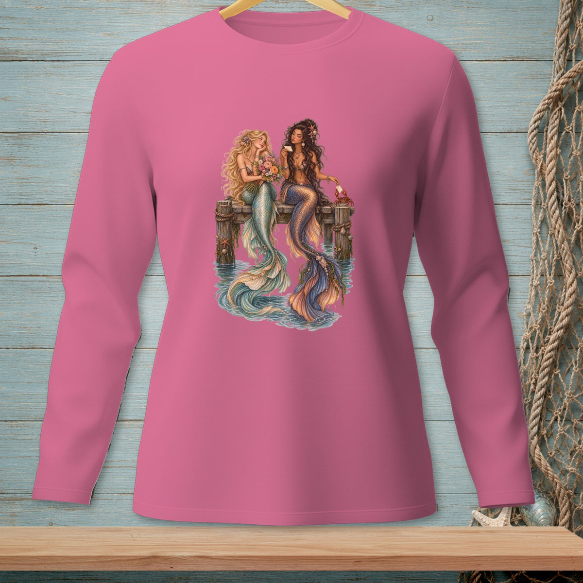 Two mermaids sit on a pier, one holding flowers, with water and a net in the background.