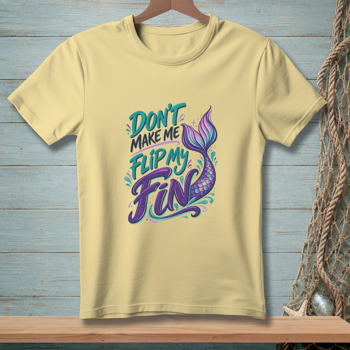 Pale yellow t-shirt with "Don't Make Me Flip My Fin" text and mermaid tail graphic.