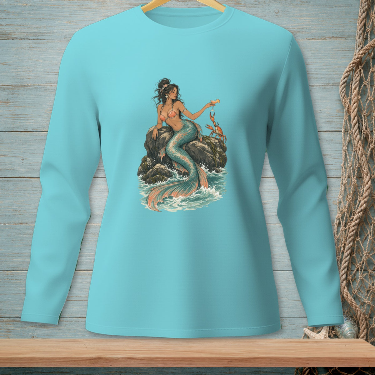Teal long-sleeve shirt with a graphic of a mermaid sitting on a rock with a crab.