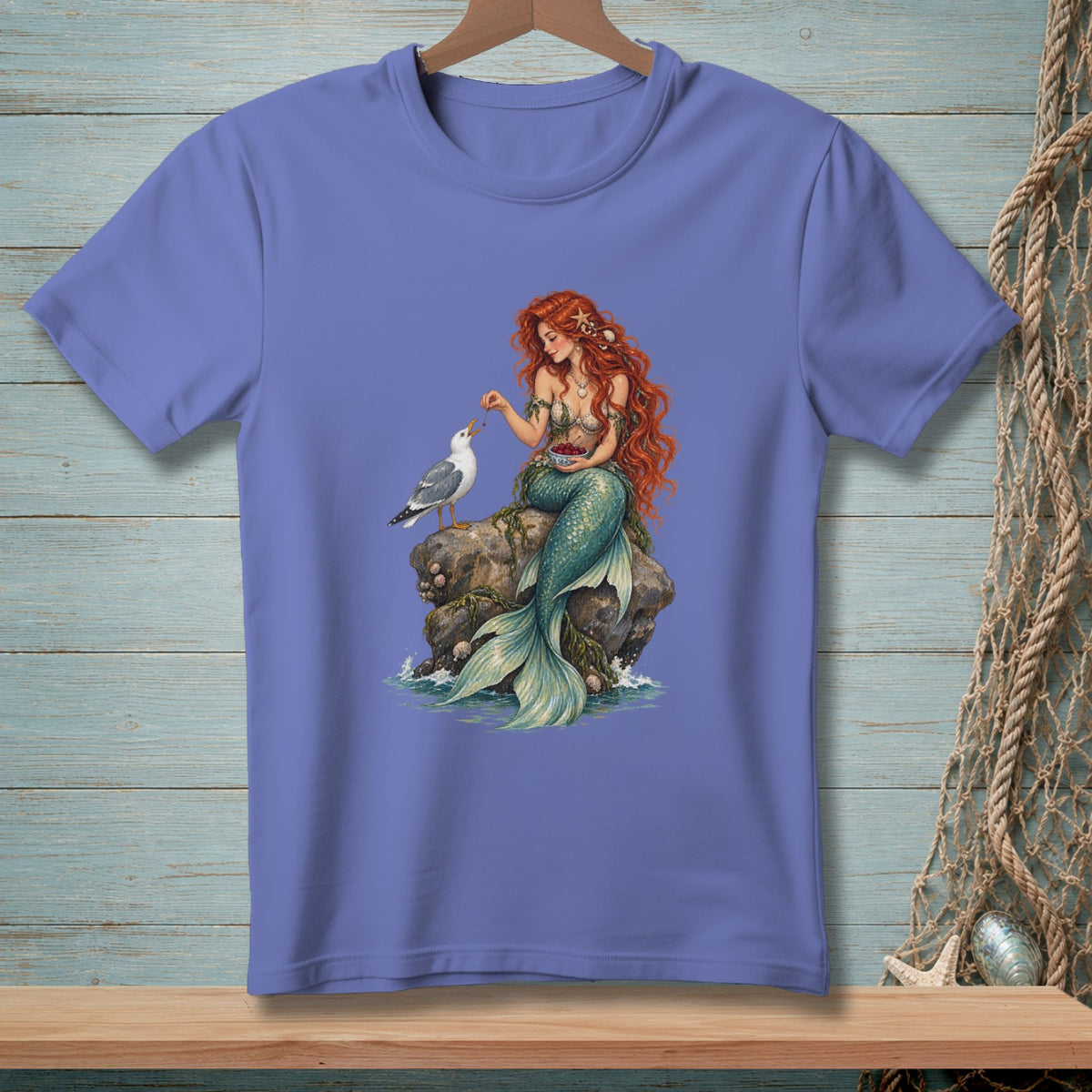 Mermaid with red hair feeding a seagull berries while sitting on a rock.